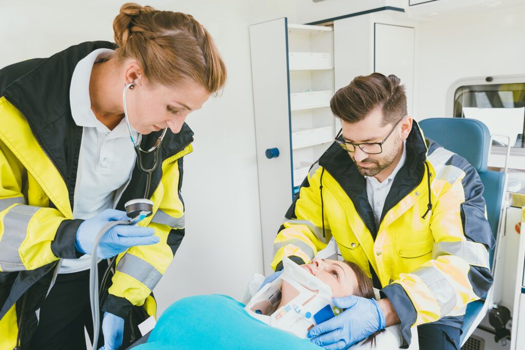 Medic taking care of injured woman with whiplash in ambulance