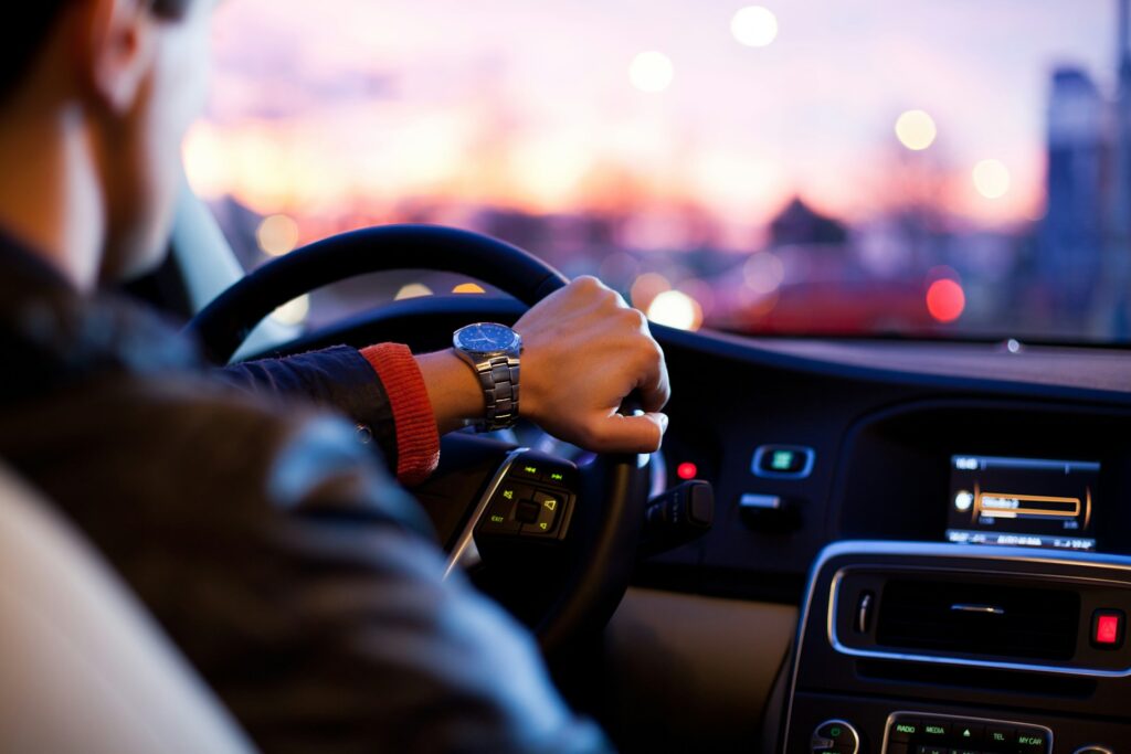 man driving car with hand on wheel