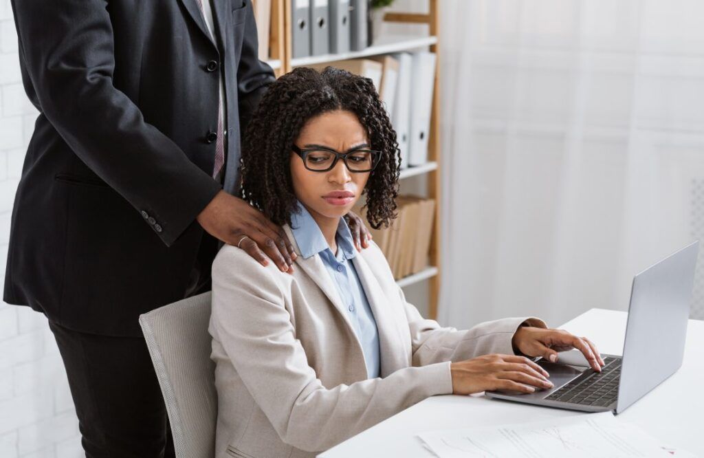 man putting his hands on female employee's shoulders