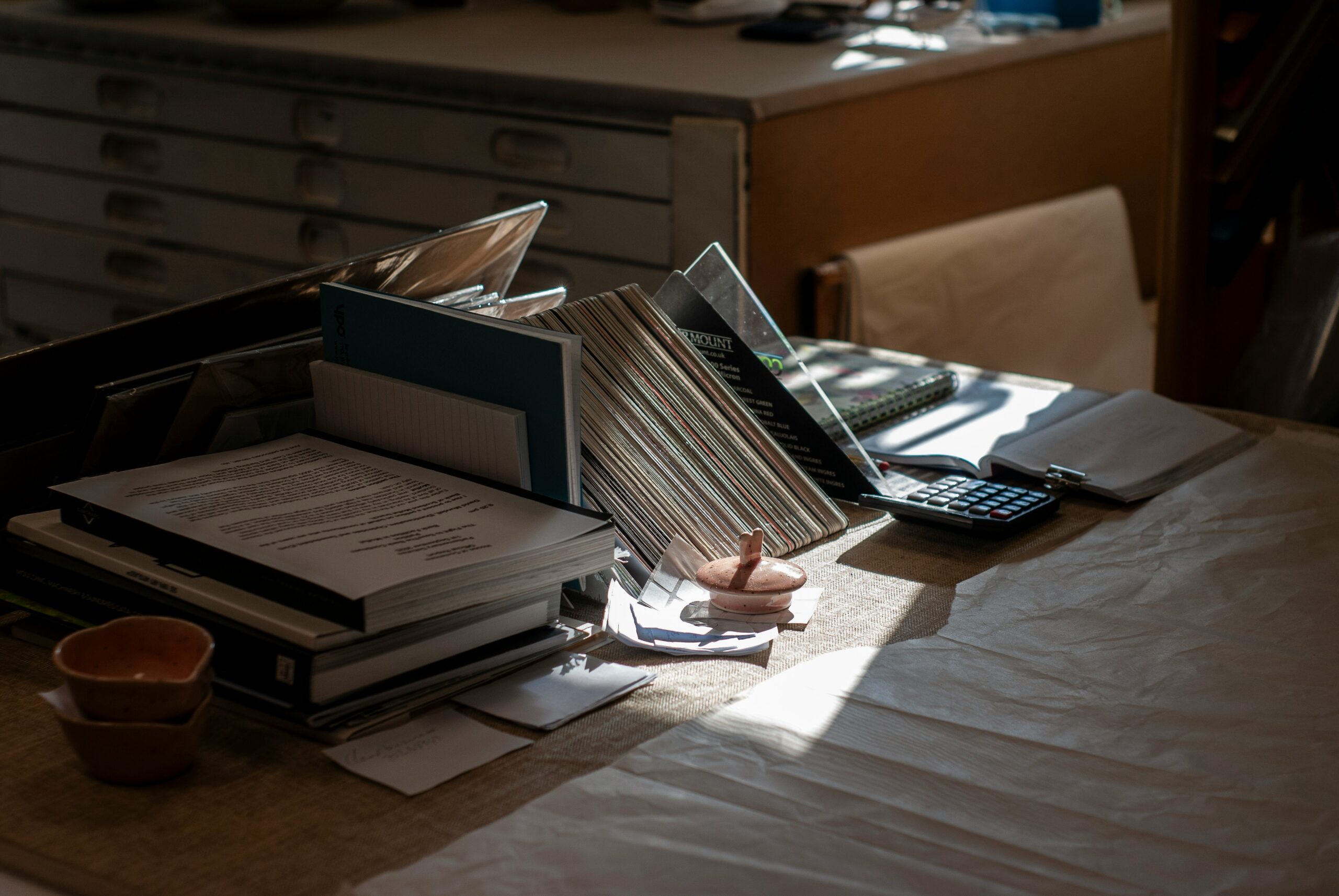 A desk featuring a laptop surrounded by a stack of books, creating a study or work environment.