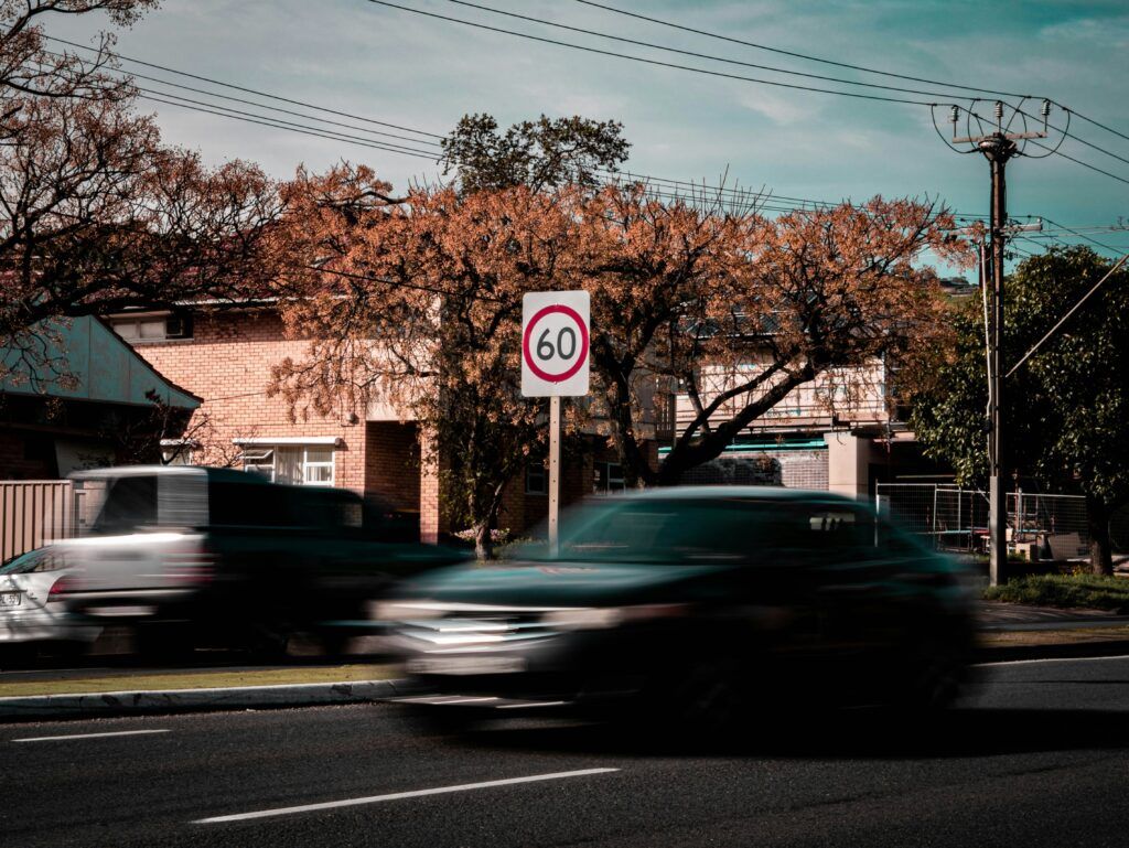 A street scene featuring a no parking sign with a car driving past it.
