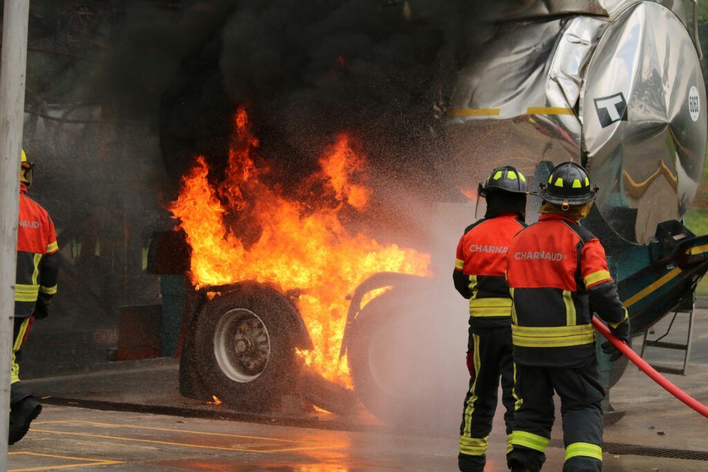 Firefighters gather around a burning truck, actively working to extinguish the flames and ensure safety.