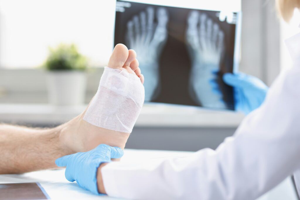 A doctor examines a bandaged foot, focusing on the injury during a medical consultation.