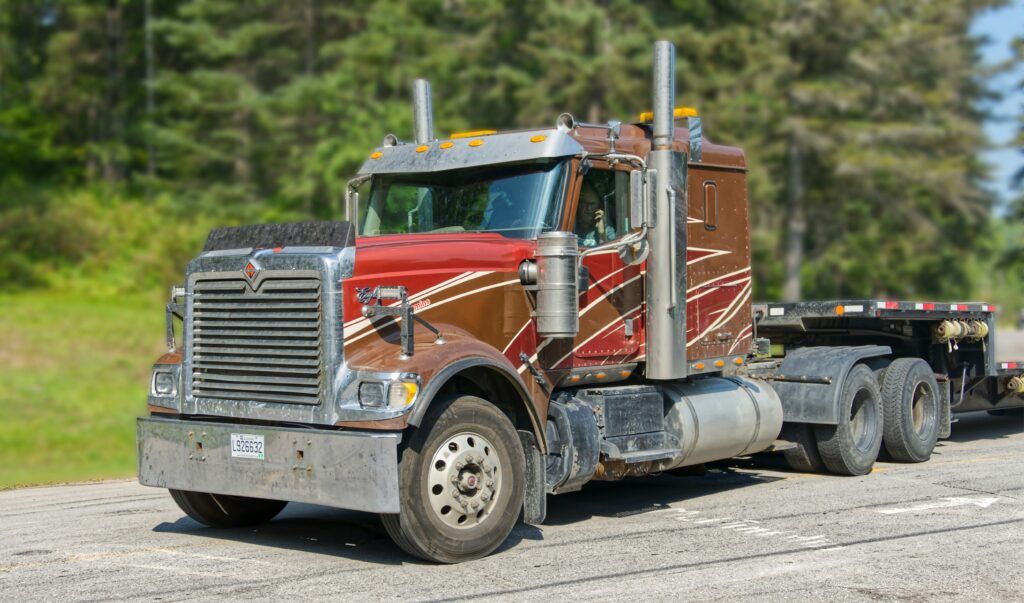 A large semi truck with a flatbed trailer parked on a highway, showcasing its cargo area and robust design.