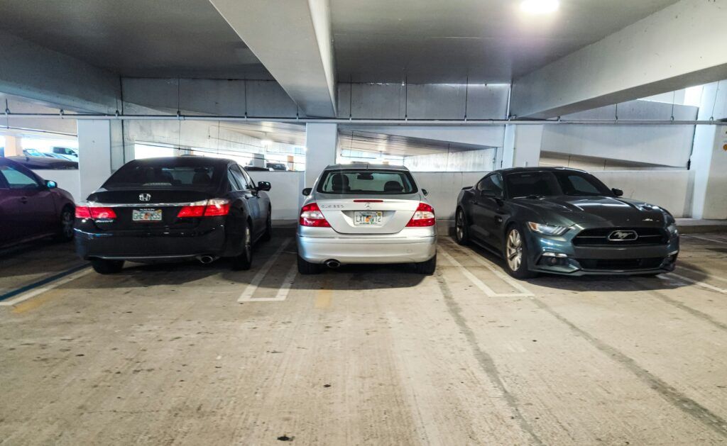 Three cars parked in a dimly lit parking garage, showcasing a typical urban parking environment.